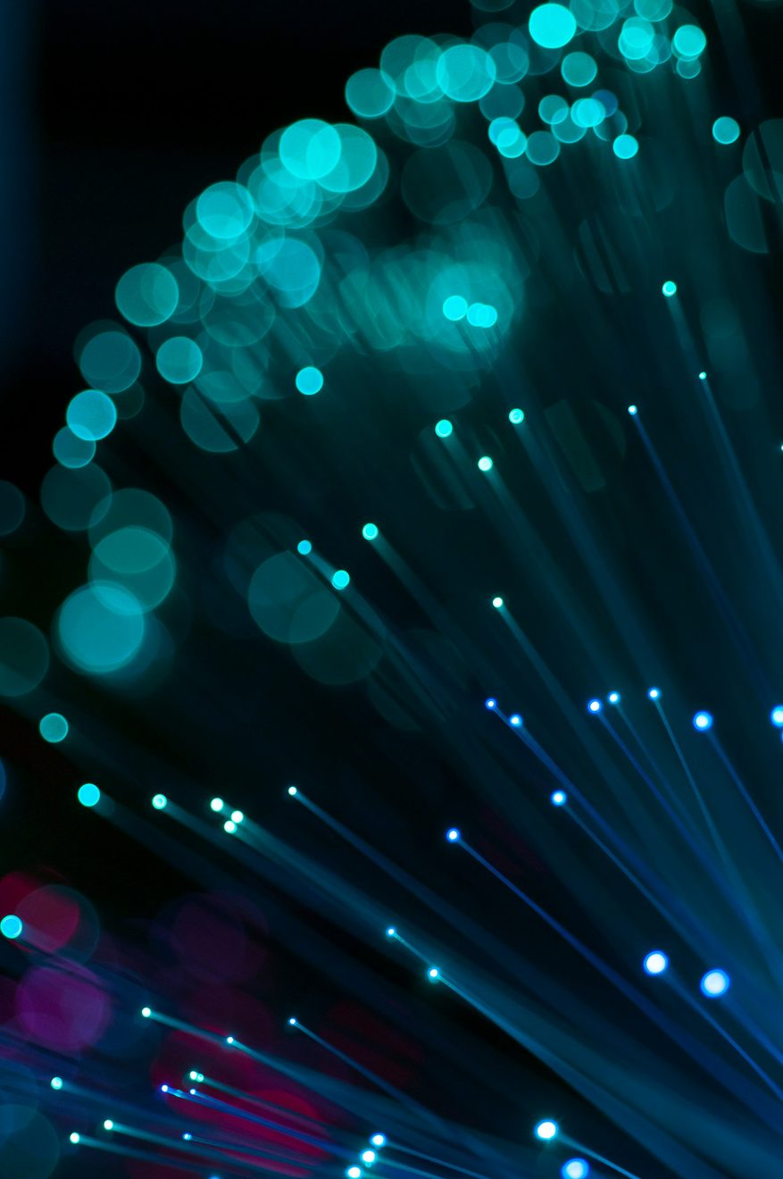Close-up of teal and magenta fibre optic strands with soft glowing points of light